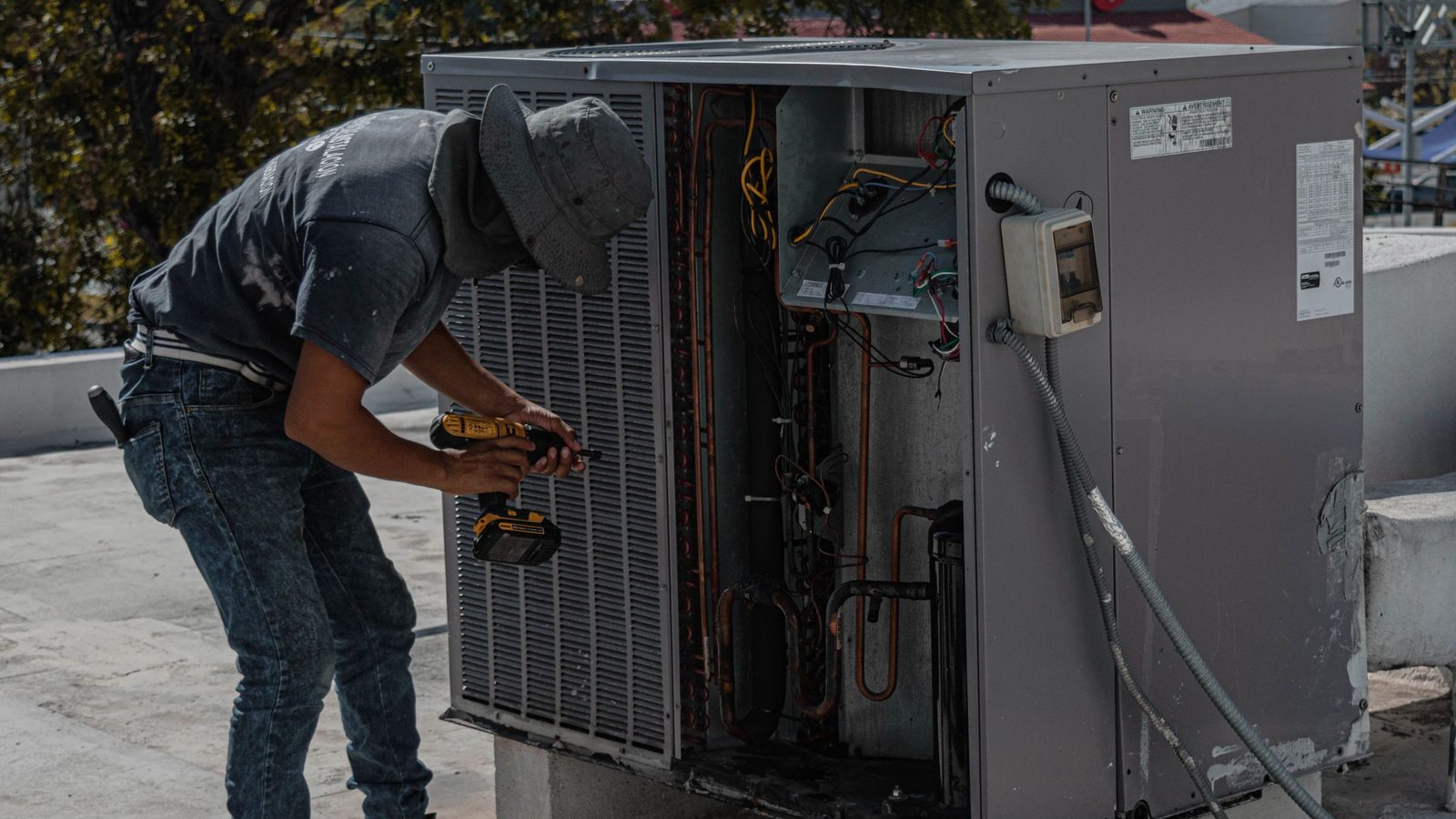 HVAC technician working on an open rooftop condensing unit